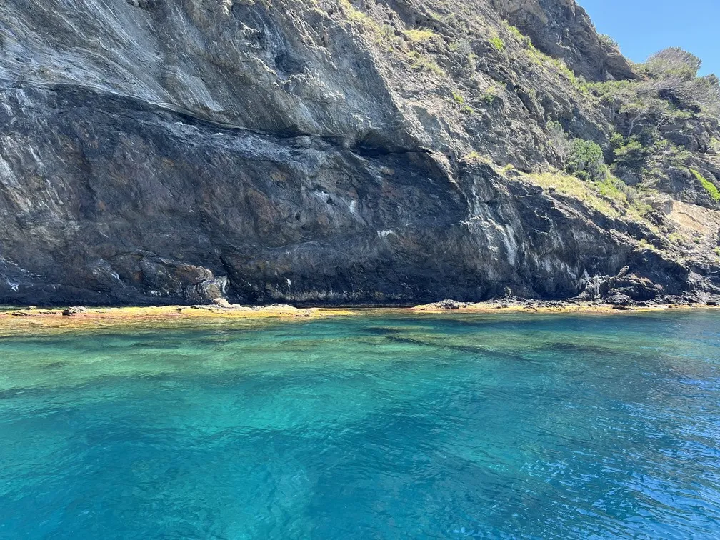Vista des del vaixell amb paisatge rocós del Cap de Creus i gent gaudint del mar