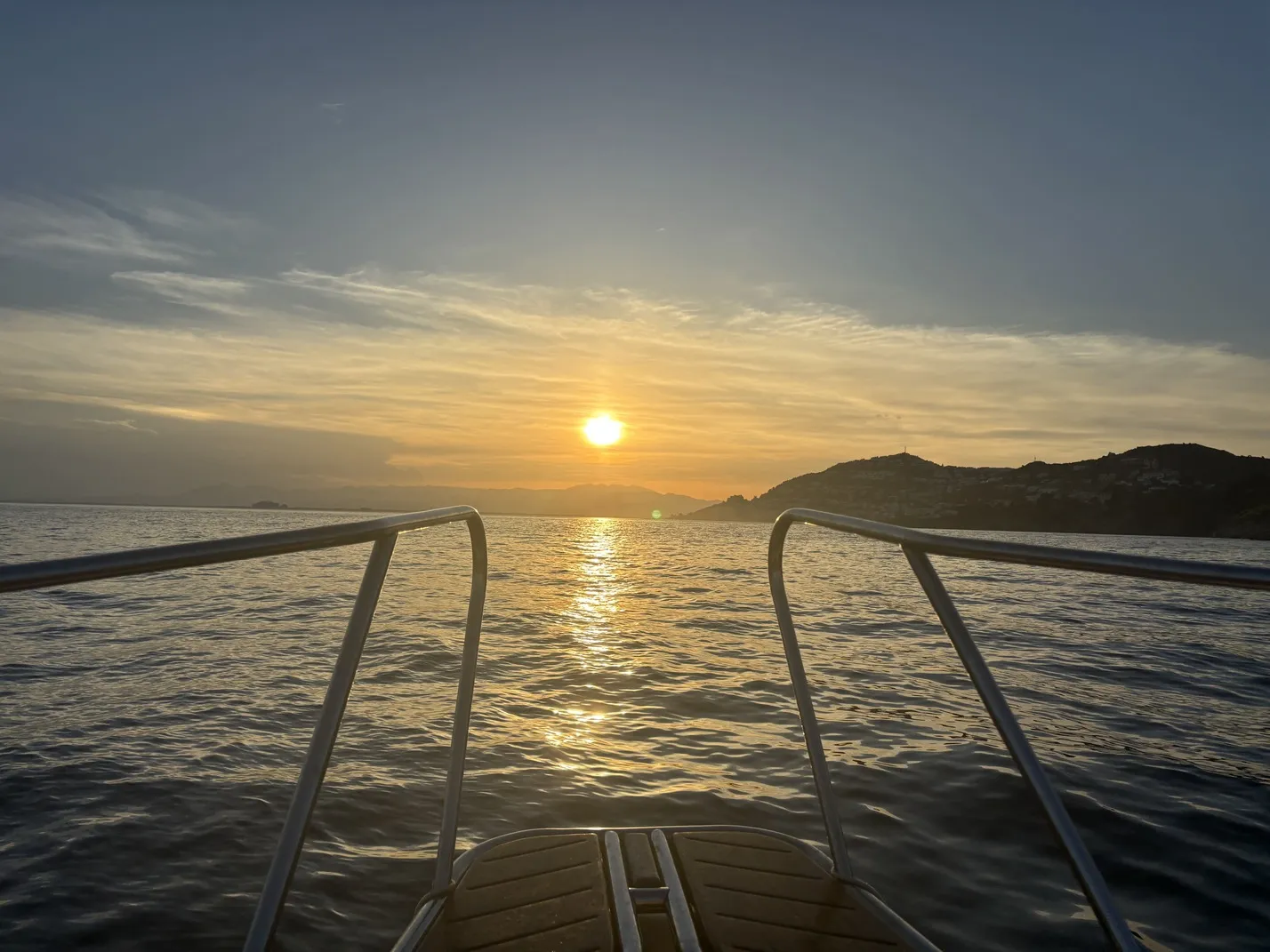 Posta de sol des del mar amb parella brindant a bord del vaixell